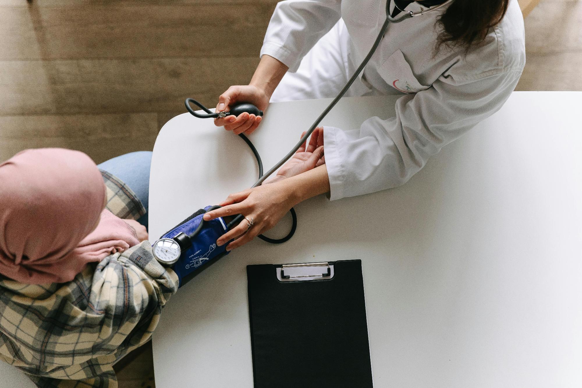 A clinician taking a patient's blood pressure at a desk